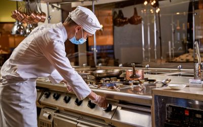 Young kitchen worker twisting cooker knob on the right and turning on fire on one burner